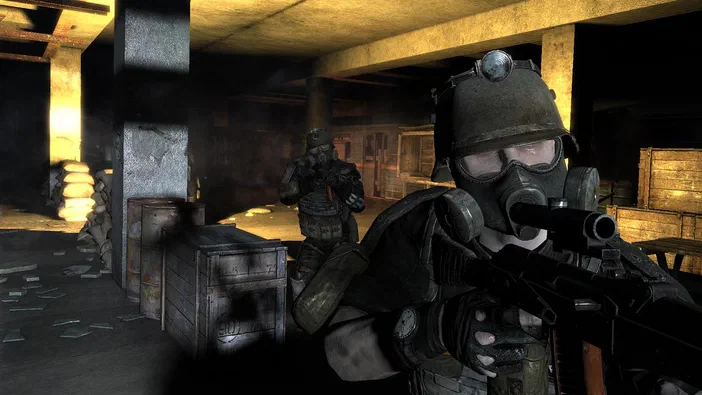 Un soldat en casque et masque à gaz tenant une arme de guerre se tient au premier plan dans les souterrains sombres du jeu vidéo Metro 2033, entouré d'autres combattants et de matériel.