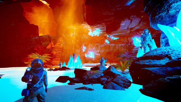 Dans The Planet Crafter, plusieurs personnages en combinaison spatiale explorent une grotte colorée où les rochers sombres côtoient une végétation brillante sous un éclairage contrasté entre zones rouges et bleues.