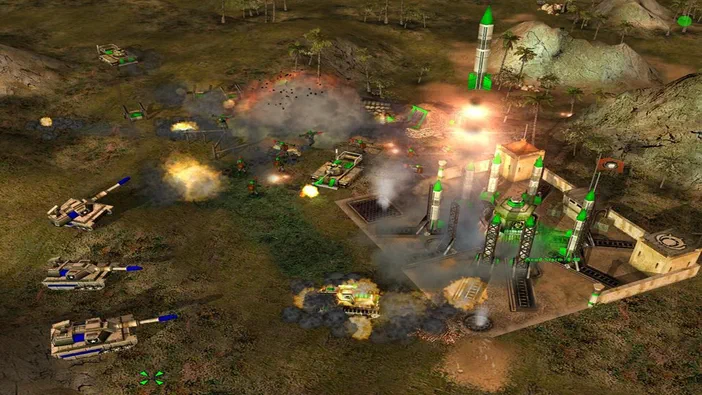 Capture d'écran du jeu vidéo Command & Conquer™: Generals montrant des véhicules blindés et des installations militaires en feu dans un environnement tropical.