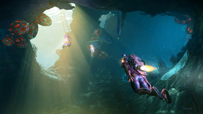 Dans No Man's Sky, des personnages en combinaison spatiale se déplacent dans un environnement sous-marin aux grands récifs coralliens colorés avec une lumière naturelle venant d'une ouverture.