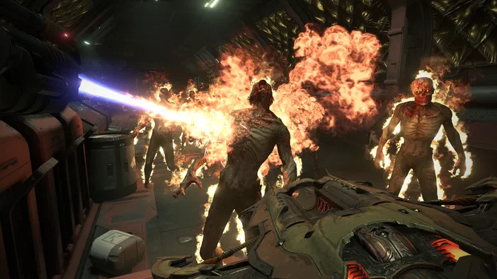 Dans DOOM Eternal, une vue de première personne montre un joueur tirant d'un fusil à plasma sur des démons enflammés dans l'intérieur d'un vaisseau spatial.