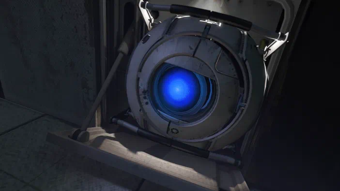 Capture d'écran du jeu vidéo Portal 2 montrant le compagnon sphérique de l'IA GLaDOS, un petit robot blanc à l'œil bleu lumineux.