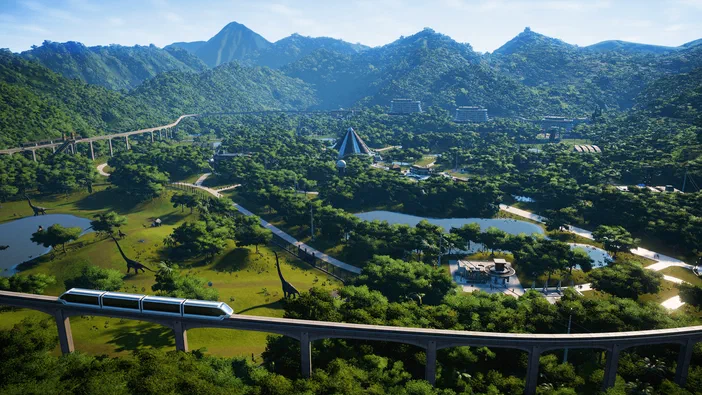 Vue aérienne d'un parc dinosaure du jeu Jurassic World Evolution, montrant des longs cous dans un enclos herbeux avec des étangs et des trains circulant sur des rails élévés au pied de montagnes verdoyantes.