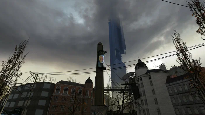 Capture d'écran du jeu Half-Life 2 montrant une ville sombre avec des lignes électriques et une tour centrale affichant un visage holographique.