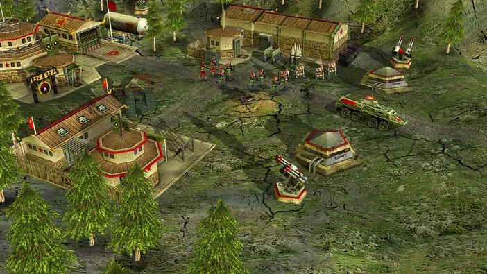 Capture d'écran du jeu Command & Conquer™ Generals Zero Hour montrant un camp militaire avec des soldats, véhicules blindés verts, canons antiaériens sur bases rouges hexagonales et bâtiments dans un paysage de terrain craquelé.