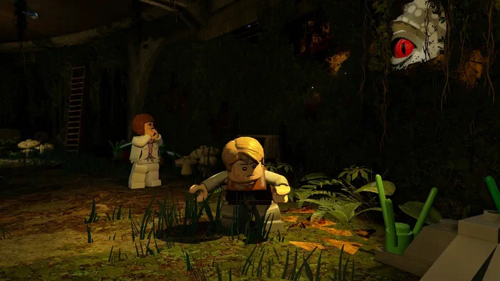 Deux minifigurines LEGO se tiennent prudemment au milieu de la végétation dense, tandis qu'une créature aux yeux rouges observe depuis l'ombre dans le jeu vidéo LEGO® Jurassic World.