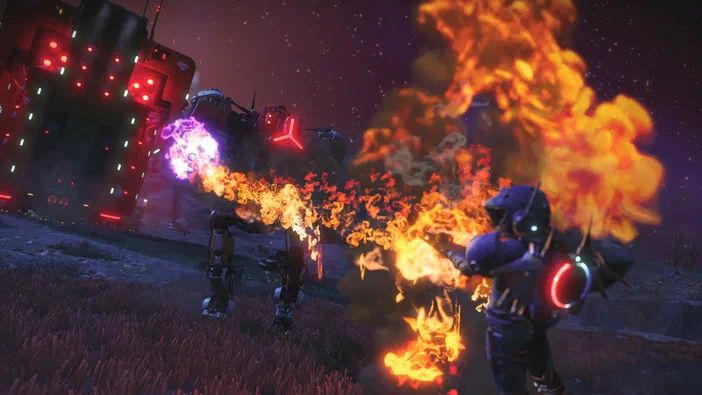 Dans No Man's Sky, un personnage en armure bleue tire une arme à flamme orange devant un robot bipède émettant des jets violets dans le ciel étoilé d'un paysage extraterrestre.