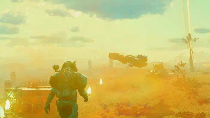 Dans le jeu vidéo No Man's Sky, un personnage en combinaison spatiale se tient au premier plan d'un paysage désertique jaune et orange sous un ciel nuageux, avec des véhicules flottants visibles à l'arrière-plan.
