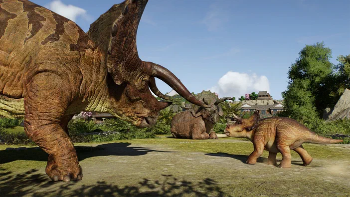 Capture d'écran de Jurassic World Evolution 3 montrant un grand Tricératops brun face à deux autres dinosaures plus petits sur une pelouse verte.