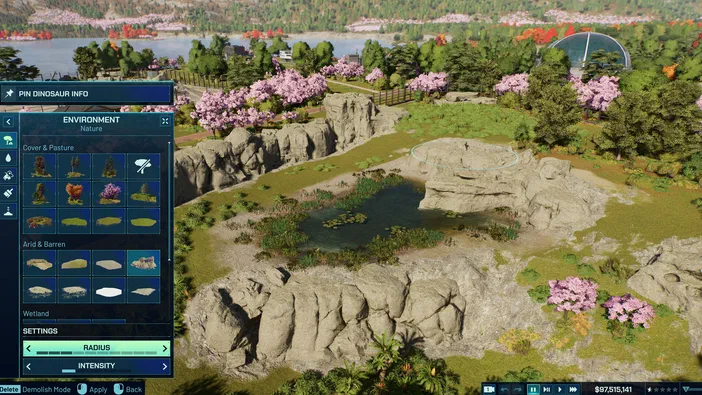 Capture d'écran du jeu vidéo Jurassic World Evolution 3 affichant une vue sur un parc naturel virtuel composé de rochers, d'un étang et d'arbres à fleurs roses, accompagnée d'une interface utilisateur permettant de modifier les éléments environnementaux comme le pâturage ou les zones arides.