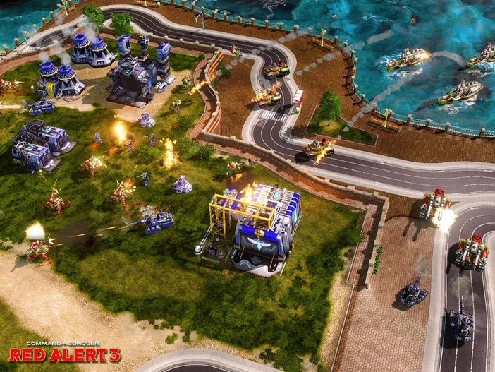 Capture d'écran montrant un combat de stratégie en temps réel avec des véhicules et des bâtiments explosifs sur une carte côtière dans le jeu vidéo Command & Conquer Red Alert 3.
