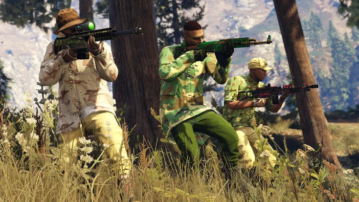 Capture d'écran de Grand Theft Auto V montrant trois personnages en tenue camouflage tenant des armes à feu dans un décor extérieur herbeux et montagneux.