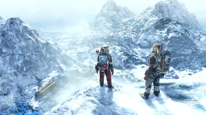 Deux astronautes en combinaison rouge et blanche observent un paysage montagneux enneigé dans le jeu vidéo No Man's Sky.