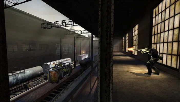 Dans Counter-Strike: Source, un joueur tire une arme dans un entrepôt sombre avec des wagons de marchandises sur les rails à gauche.