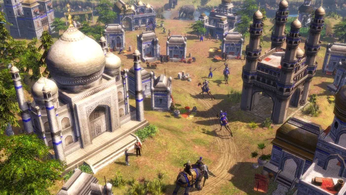 Vue aérienne d'une ville dans le jeu Age of Empires III avec des bâtiments indiens et des cavaliers.