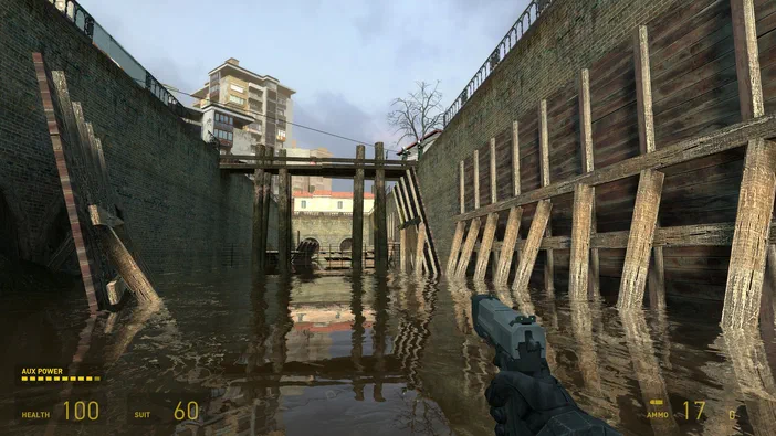 Capture d'écran de Half-Life 2 montrant un personnage tenant une arme dans un canal inondé bordé de murs en briques et de poutres en bois.