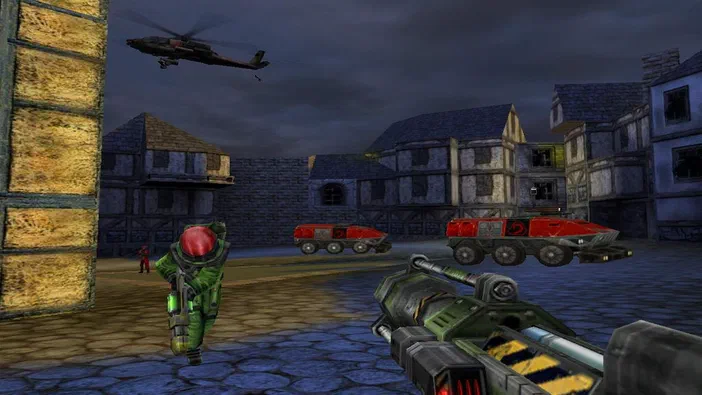 Capture d'écran du jeu Command & Conquer : Renegade montrant un soldat en tenue verte et casque rouge tenant une arme lourde dans une rue pavée avec des véhicules rouges, des bâtiments médiévaux et un hélicoptère au-dessus.