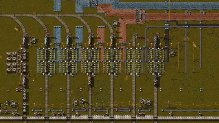 Vue de dessus d'une base complexe dans le jeu Factorio avec des trains sur des rails et une multitude d'usines.