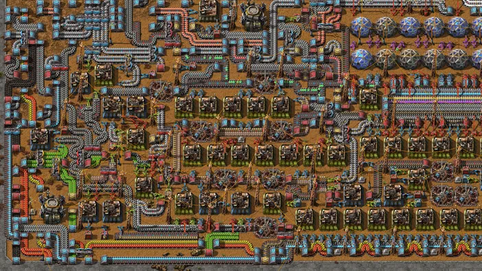 Vue d'un écran de jeu Factorio montrant une base industrielle complexe avec des tuyaux et machines.