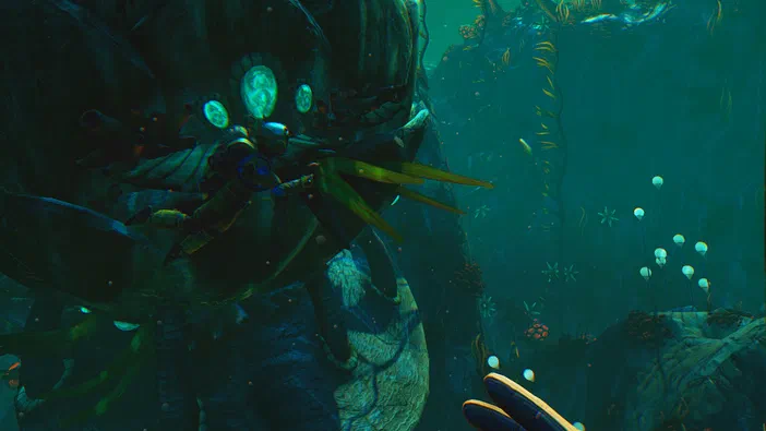 Dans No Man's Sky, un astronaute explore une planète aquatique aux couleurs vertes et bleues parsemée de végétation bioluminescente.