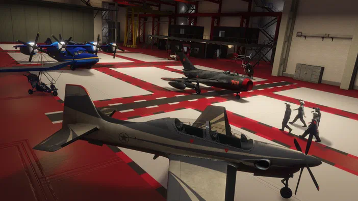 Sous-hangar de Grand Theft Auto V Legacy avec plusieurs avions et hélicoptères stationnés, dont un avion militaire gris au premier plan.