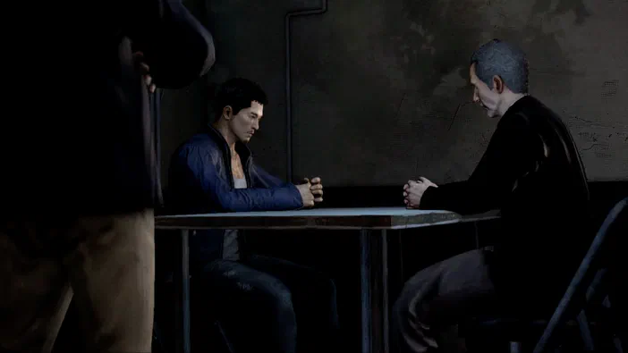 Dans le jeu Sleeping Dogs™, deux personnages masculins sont assis face à une table dans un lieu sombre et tendu.