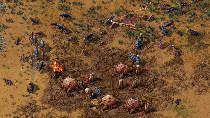 Capture d'écran du jeu Factorio montrant une base industrielle avec des robots bleus et des structures roses sur un terrain aride.