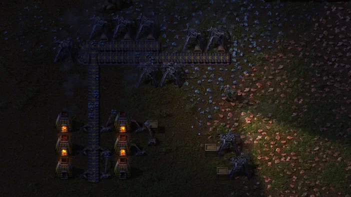 Vue de dessus d'une base industrielle dans le jeu Factorio avec des bâtiments et structures sur un terrain parsemé de ressources.