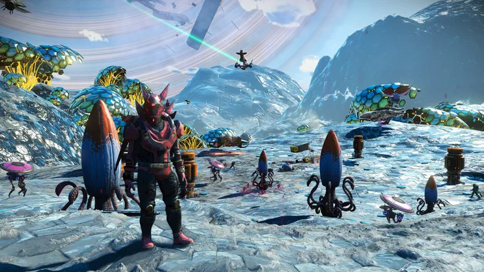 Dans le jeu vidéo No Man's Sky, un personnage en armure rouge se tient sur une planète aux rochers bleutés entouré de créatures extraterrestres colorées et d'une végétation étrange sous un ciel lumineux.