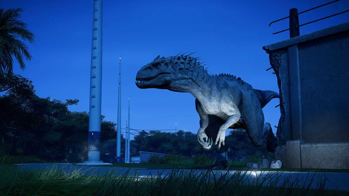Dans le jeu Jurassic World Evolution, un dinosaure à crête se tient sur une route nocturne près d'un bâtiment.