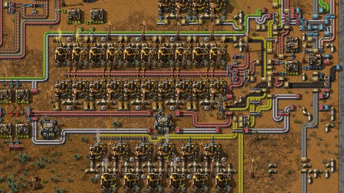 Capture d'écran du jeu Factorio montrant une base industrielle complexe avec des centaines de machines et un réseau dense de tuyauteries colorées.