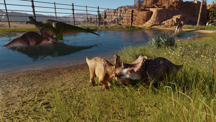 Dans le jeu Jurassic World Evolution, deux dinosaures jouent ensemble près d'un étang.
