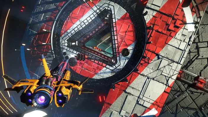Capture d'écran du jeu vidéo No Man's Sky montrant une vue en plongée sur un vaisseau spatial jaune et violet devant des structures géométriques rouges, noires et grises.