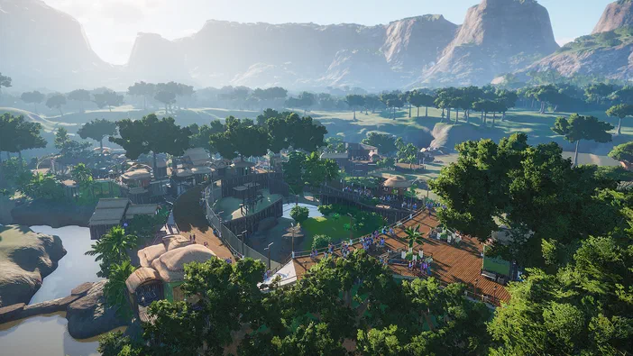 Vue aérienne d'un zoo dans le jeu Planet Zoo avec des enclos pour animaux et des visiteurs.