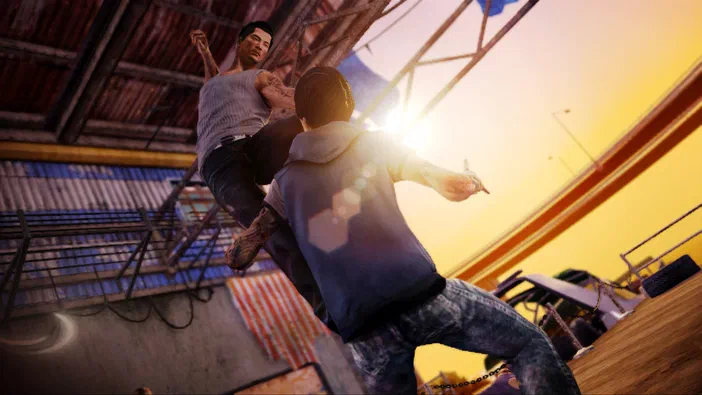 Dans le jeu Sleeping Dogs™, un personnage en haut de corps effectue une frappe aérienne sur son adversaire dans un environnement industriel baigné d'une lumière dorée.