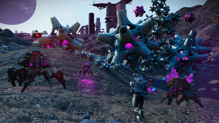 Dans le jeu vidéo No Man's Sky, un explorateur et des robots avancent sur une planète extraterrestre parsemée de formations rocheuses émettant une lueur violette.