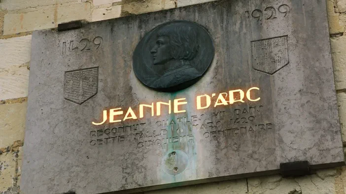 Plaque commémorative en pierre avec le nom de Jeanne d'Arc et une date.