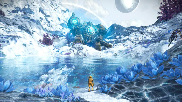 Dans le jeu vidéo No Man's Sky, un personnage en combinaison jaune observe une structure géante bleue émettant de la lumière au bord d'un lac gelé sous deux lunes.