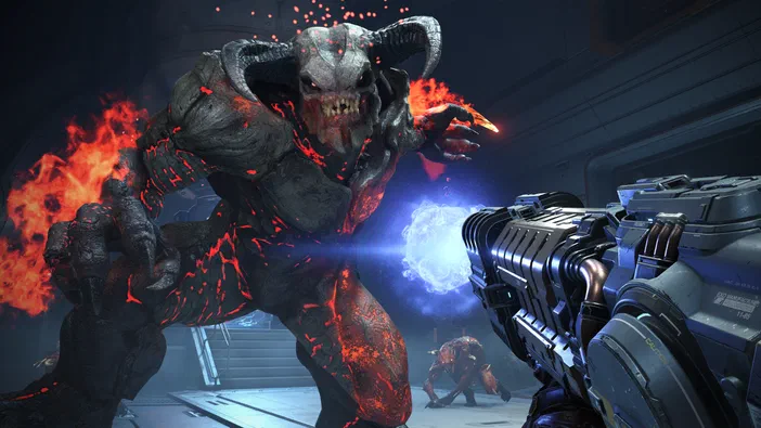 Dans DOOM Eternal, le joueur vise un démon de pierre enflammé avec une arme futuriste dans un environnement industriel sombre.