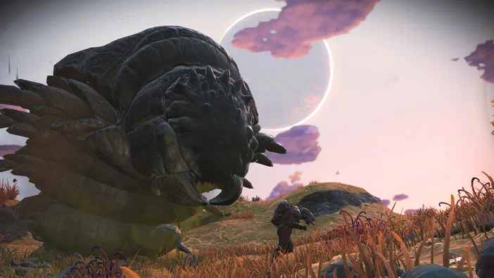 Dans le jeu vidéo No Man's Sky, un vaisseau spatial se tient sur une planète aux herbes dorées sous un ciel rose avec des nuages violets et deux lunes en arrière-plan.