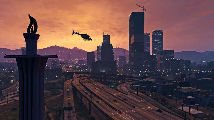 Vue de la ville au coucher du soleil dans Grand Theft Auto V avec une hélicoptère en vol et des autoroutes.