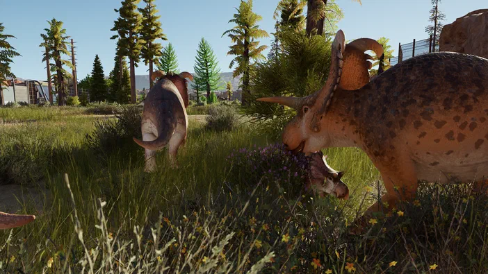 Dans le jeu Jurassic World Evolution, un jeune dinosaure tricératops câliné par sa mère dans une prairie ensoleillée.