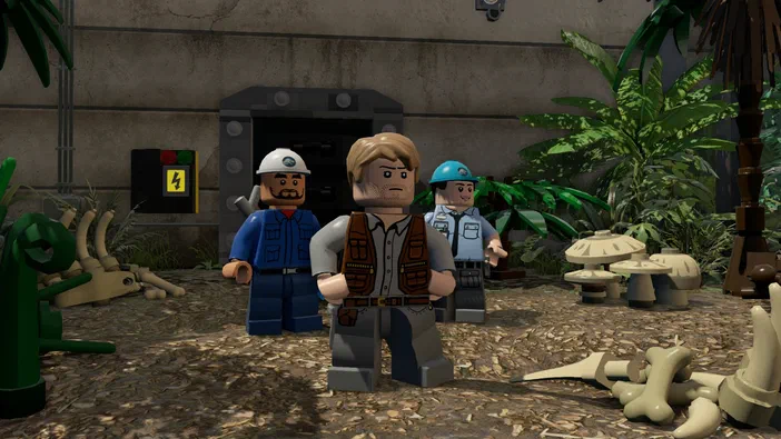 Capture d'écran du jeu LEGO Jurassic World montrant trois personnages en briques dans un décor de jungle avec des ossements.