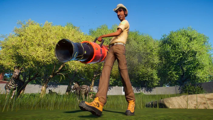 Dans le jeu Planet Zoo, un gardien portant une casquette et des bottes orange utilise un souffleur à feuilles devant deux zèbres dans une savane ensoleillée.