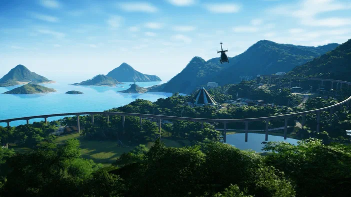 Capture d'écran de Jurassic World Evolution montrant une île verdoyante avec un hélicoptère survolant des montagnes et une structure pyramidale.