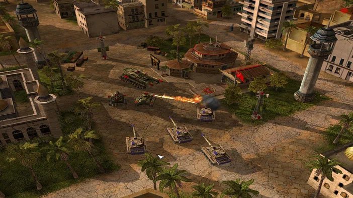 Capture d'écran de Command & Conquer™: Generals montrant des chars en combat dans une ville avec des palmiers et des bâtiments.