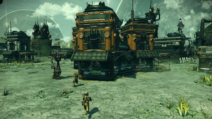 Dans le jeu vidéo No Man's Sky, un personnage en armure jaune marche sur une planète désertique vers des structures industrielles orange et noires sous un ciel verdâtre.