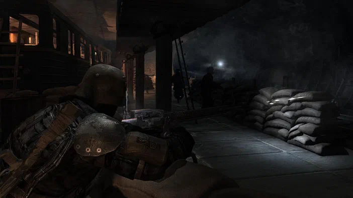 Dans le jeu vidéo Metro 2033, un soldat en armure se tient près d'un train dans une gare souterraine sombre avec des sacs de sable.