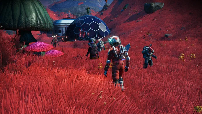 Dans le jeu vidéo No Man's Sky, plusieurs explorateurs en combinaison spatiale marchent dans un champ rouge vif parsemé de fleurs jaunes et d'immenses champignons verts.