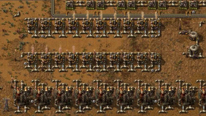 Vue de dessus d'une base Factorio avec des lignes de machines et de cheminées sur un terrain aride.